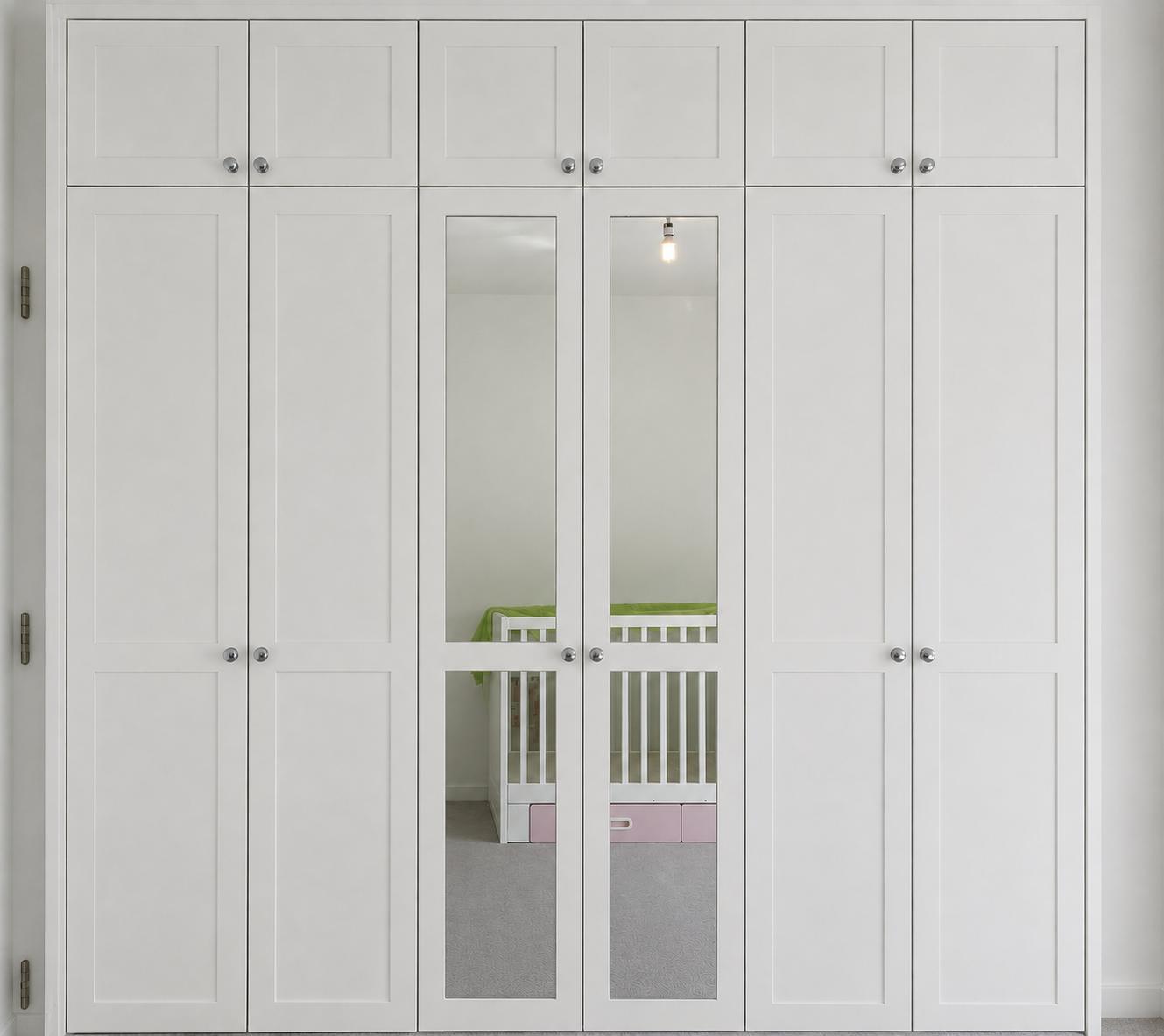 White fitted wardrobes with mirrored centre doors and overhead cupboards